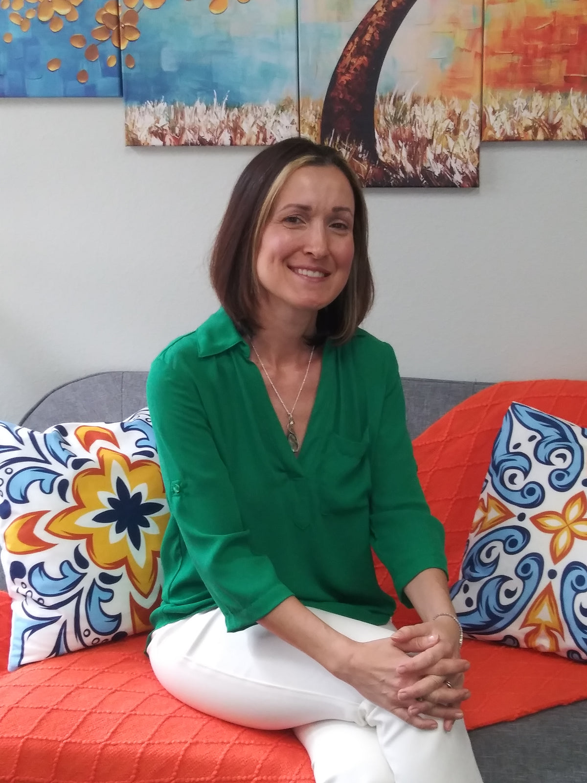 Woman sitting on a colorful couch with a patterned wall behind her